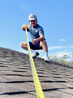 ALT="Edwin Nichols, owner of Altitude Roofing, on a roof with measuring tape"