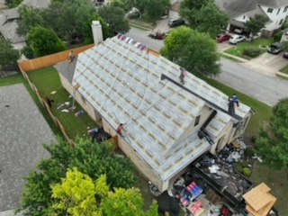 Aerial drone view of a home prepared with a waterproof underlayment barrier during a full reroof.
